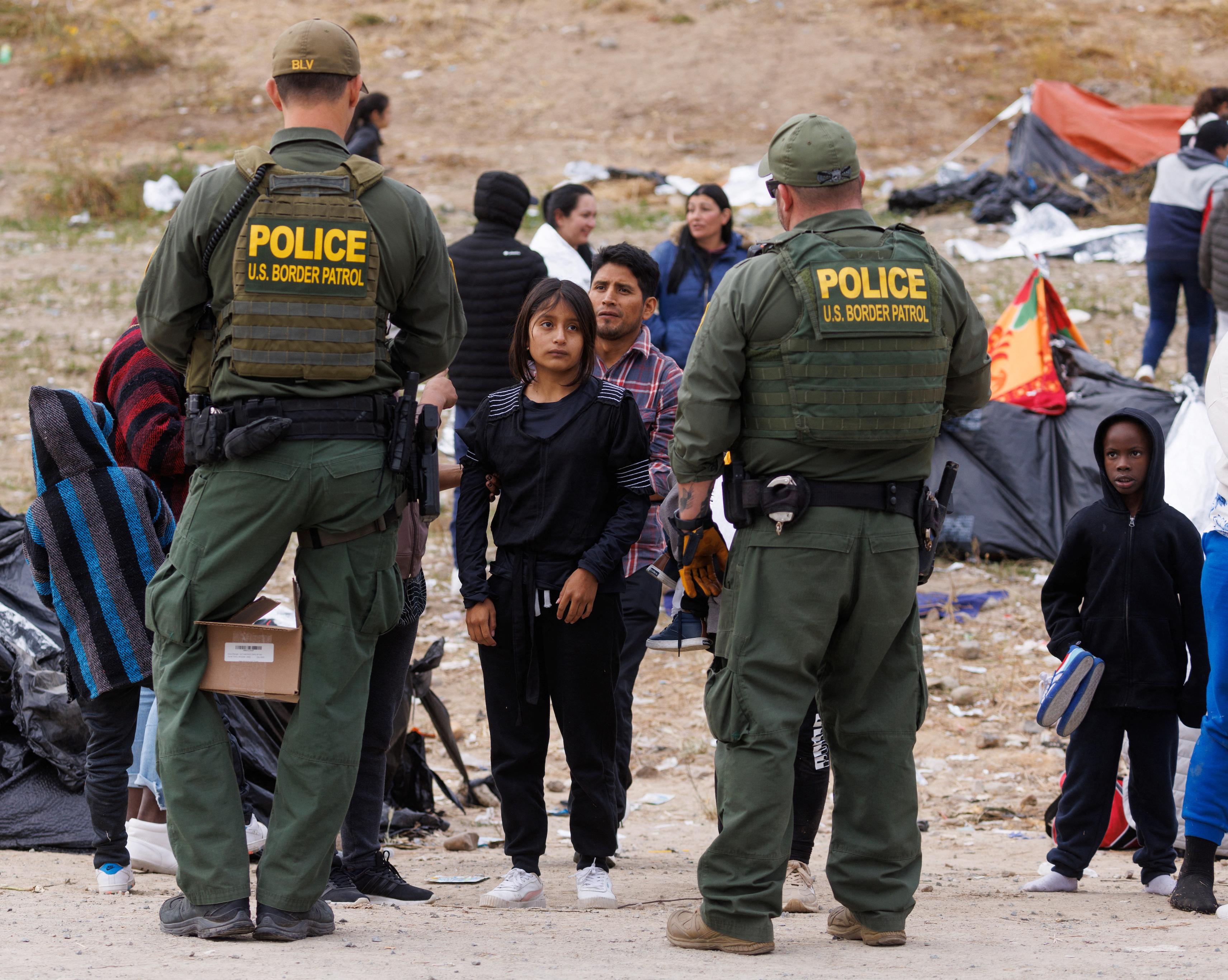 U.S. border patrol agents watch over migrants gathered between the primary and secondary border fences near San Diego, California, as the U.S. prepares to lift COVID-era Title 42 restrictions