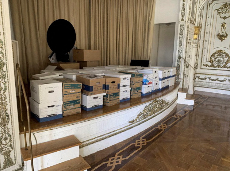 A photo published by the U.S. Justice Department in their charging document against former U.S. President Donald Trump shows what the Justice Department says are boxes of documents stored on the stage of the White and Gold Ballroom at Trump's Mar-a-Lago club in Florida in early 2021 as seen in the document released by the Justice Department in Washington, U.S. June 9, 2023. The Justice Department said they redacted the image to obscure the identity of a person in the photo.
