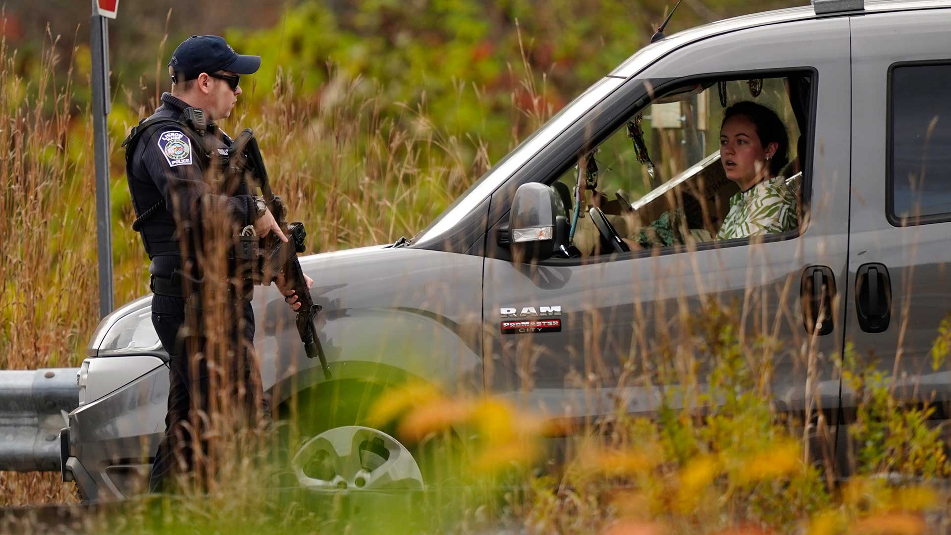 Police officers stop to question a driver at a roadblock, Thursday, Oct. 26, 2023, in Lisbon, Maine, during a manhunt for the suspect of Wednesday's mass shootings. (AP Photo/Robert F. Bukaty)