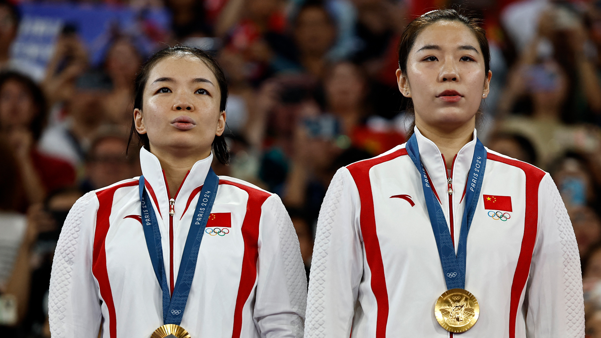 China's gold medallists Chen Qingchen (L) and Jia Yifan stand up for the Chinese national anthem on the podium with their medals during the women's doubles badminton medal ceremony at the Paris 2024 Olympic Games at Porte de la Chapelle Arena in Paris, France, August 3, 2024. /CFP